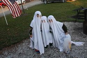 Picture of 3 children dressed as ghosts.