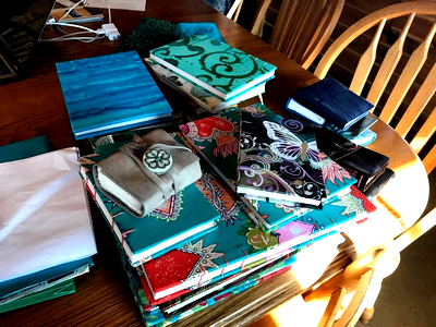 Picture showing many colorful journals piled on a table.