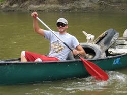Man paddling a canoe with trash fished from the Boone River.